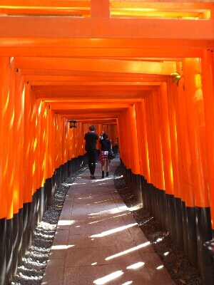 伏見稲荷大社の千本鳥居。前方にカップルが歩いている。