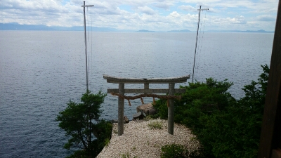 外に立つ鳥居に向かってかわらけを投げる